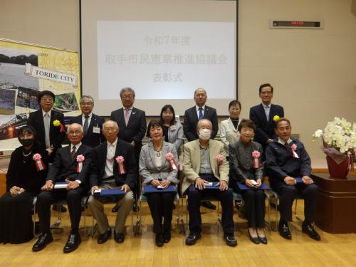 令和7年度受彰者の皆さん 前列左から小玉様、佐々木様、澤田石様、武井様、松永様、桑ちゃんクラブ(代表 西塚様)、新取手地区自主防災会(代表 齋藤様)、後列左から釼持様、石塚教育長、中村市長、間宮会長(取手市市民憲章推進協議会)、岩澤議長、中村様、原様